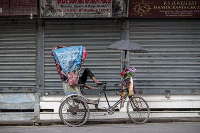 Un tirador de richshaw descansa frente a las tiendas cerradas de un mercado del distrito turístico de Thamel, en Katmandú (Nepal).