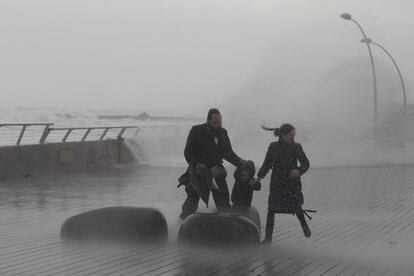 Una familia huye de las olas durante el temporal de fuertes vientos y olas que azota Tel Aviv (Israel).