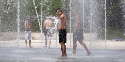 Gente refrescandose en la fuente del parque Juan Carlos I de Madrid.