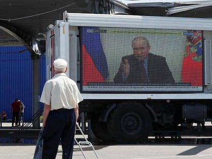 Dos ciudadanos ven un mensaje televisado de Putin en una calle de Mariupol.