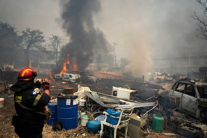 Un bombero frente a dos coches consumidos por las llamas durante los incendios de Grecia, este miércoles.