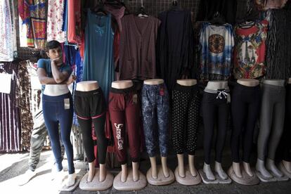 Un joven se apoya sobre un maniquí junto a un puesto de ropa en un mercado en Jerusalén (Israel).