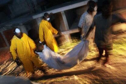 Trabajadores haitianos trasladan el cadáver de un muerto por el cólera en un cementerio en Puerto Príncipe.