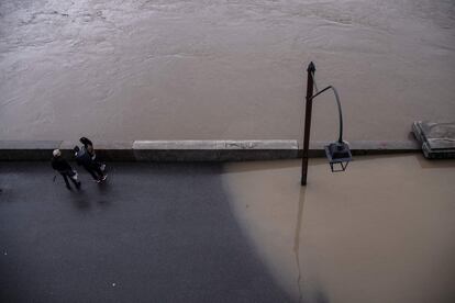 Dos permosas permacen junto a una orilla inundada por el desborde del río Po, en el centro de la ciudad de Turín.