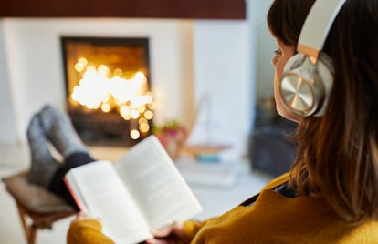 Una mujer con altavoces leyendo en un saln.