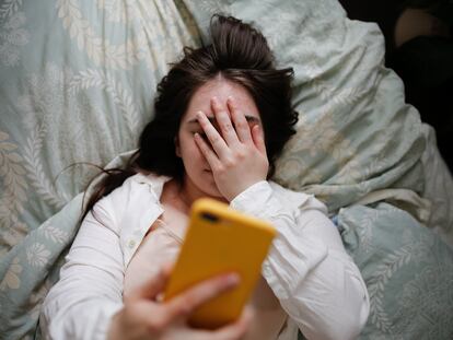 Una mujer en la cama observa su teléfono.