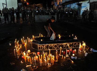 Una partidaria de Zelaya coloca una vela delante del cordón policial cerca de la Embajada de Brasil.