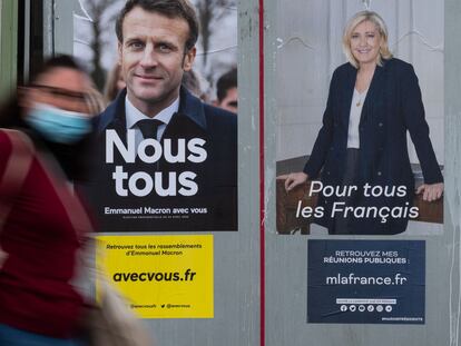 Una mujer pasa frente a los carteles electorales de Emmanuel Macron y Marine Le Pen.