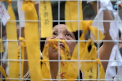 Una mujer ata lazos amarillos con mensajes en apoyo de los jóvenes manifestantes contrarios a la ley de extradición en Hong Kong (China), el 17 de julio de 2019. Cientos de ancianos pertenecientes al grupo 'Clan del Pelo Plateado' se unieron a una marcha silenciosa iniciada este miércoles en la sede del Gobierno hongkonés para pedir a la administración que escuche las demandas del pueblo, elimine el proyecto de ley de extradición a China y libere a los manifestantes arrestados durante las marchas.