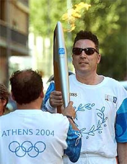 El cantante Loquillo pasa el fuego olimpico a otro relevista durante el paso de la antorcha olímpica por Barcelona, que ha concluido en las fuentes de Montjuoc, donde se ha celebrado una gran fiesta de <i>Dragones y diablos</i>, con la presencia de 1.500 niños nacidos en 1992.