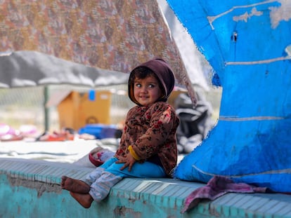 Una niña desplazada afgana sonríe bajo las lonas de la tienda en la que vive temporalmente en un parque de Kabul.
