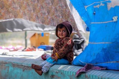 Una niña desplazada afgana sonríe bajo las lonas de la tienda en la que vive temporalmente en un parque de Kabul.