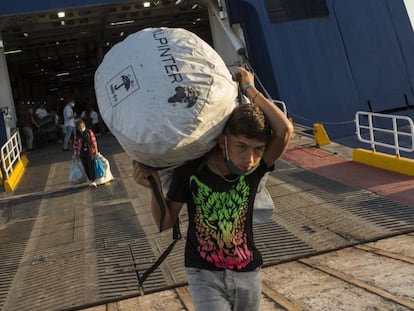 Refugiados del campamento incendiado de Moria en Lesbos desembarcan en un ferry en el puerto de Lavrio para ser trasladados a otro asentamiento en la Grecia continental.