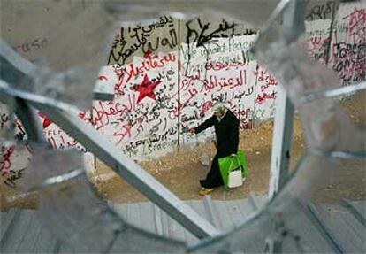 Una mujer palestina, vista a través de una ventana, mientras camina junto al muro, de ocho metros de altura.