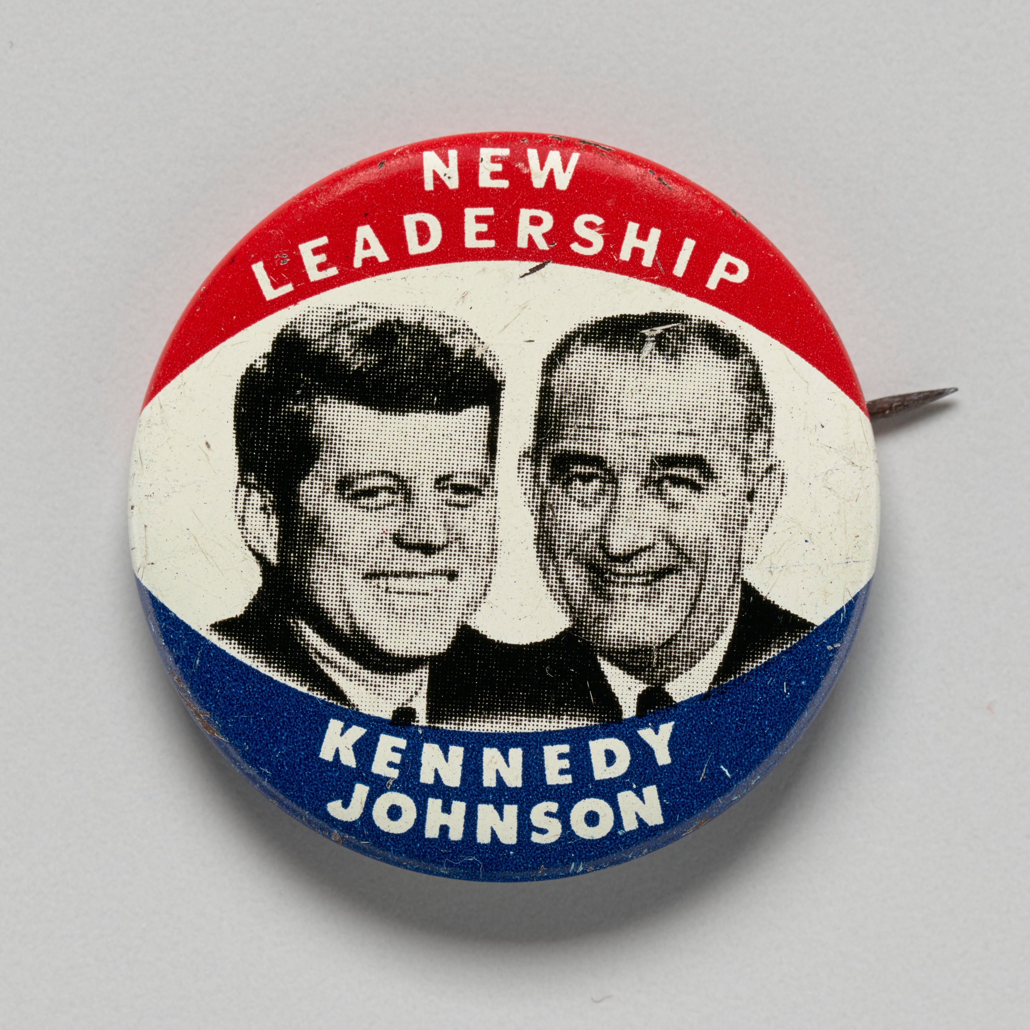 A 1960 presidential campaign pinback button with the faces of John F. Kennedy and running mate Lyndon B. Johnson. Kennedy ran as a candidate of the Democratic Party. Kennedy was sworn in as the 35th president of the United States in January 1961. Johnson was Vice President. The button is red, white, and blue. In the central white, elliptical-shaped band is a black-and-white graphic of Kennedy and Johnson depicted side-by-side, from the shoulders up, and facing the viewer. Both men are smiling. The red band above the white band has white text that reads, [NEW / LEADERSHIP]. The blue band below the white band has white text that reads, [KENNEDY / JOHNSON]. There are three union labels and the name of the manufacturer printed along the rounded back edges of the button. The back of the button is silver toned with a brass pin. Artist Green Duck Company. (Photo by Heritage Art/Heritage Images via Getty Images)