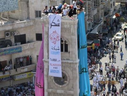 Un grupo de manifestantes anti gubernamental cuelga el cartel "Gracias Al Yazira, gracias Shaam News Network" en Hama, Siria