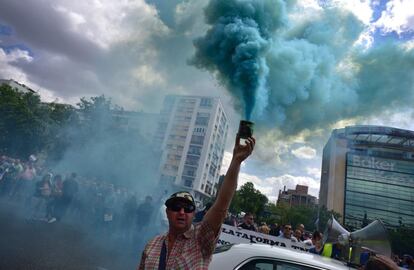 Un taxista con un bote de humo protesta contra las empresas Uber y Cabify en el centro de Madrid.
