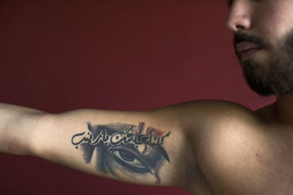 Abbas, 23 años, posa para la foto mostrando sus tatuajes de consignas religiosas chiíes, donde pone: "Todos somos su Abbas, oh Zeinab," en el sur de Beirut, Líbano.