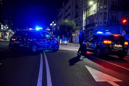 Dos coches de Policía Nacional circulan por la calle Calvo Sotelo minutos antes de la segunda noche de toque de queda, en Santander.