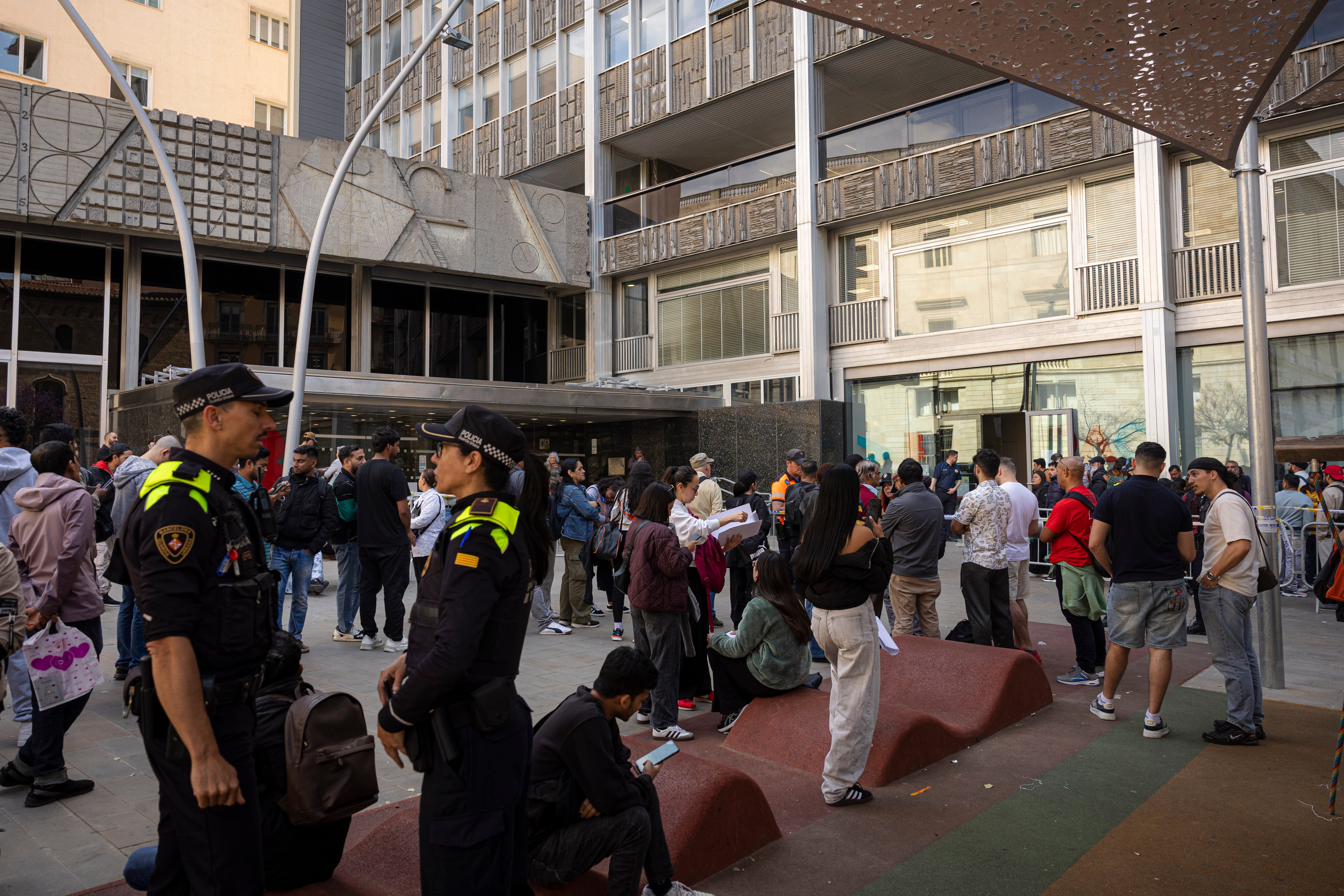 Colas frente a la OAC de Plaza Sant Miquel, frente al Ayuntamiento de Barcelona, controlados por la Guardia Urbana.