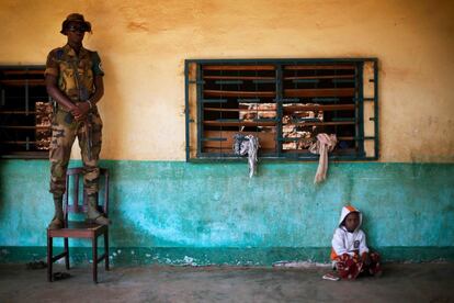 Un soldado de la fuerza de paz de la Unión Africana se encuentra encima de una silla al lado de niño sentado en el suelo en un centro islámico donde los refugiados Peul han buscado protección en Bangui, República Centroafricana.