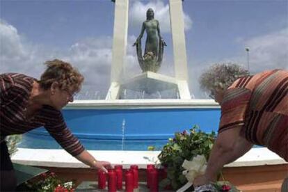 Dos mujeres colocan velas y flores en el monumento dedicado a Rocío Jurado de Chipiona.