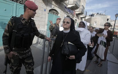 Un guardia de seguridad palestino saluda a una monja en su camino a la Plaza del Pesebre.