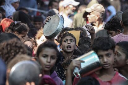 Ciudadanos palestinos esperan para recibir comida distribuida por una ONG en Deir al Balah (Gaza), el lunes.