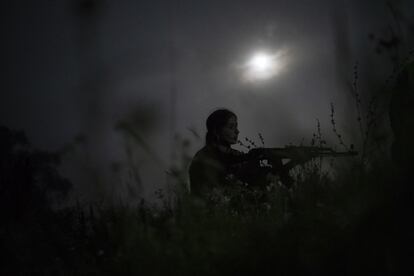 Una joven toma posición con un rifle AK-47 descargado, durante un ejercicio nocturno en las proximidades de Ternopil, el 29 de julio de 2018.