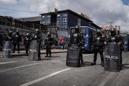 Policías de la UNDMO protegen los buses alimentadores de Transmilenio, en Molinos, al sur de Bogotá, este jueves.