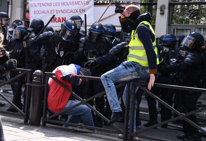 La policía golpea a un manifestante envuelto en una bandera francesa, durante las manifestaciones en París.