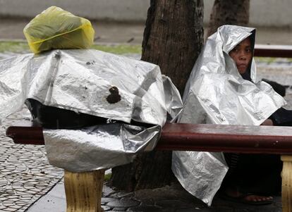 Una mujer se cubre con plásticos para refugiarse de la lluvia ala llegada del tifón "Haiyan" en Manila (Filipinas), 8 de noviembre de 2013.