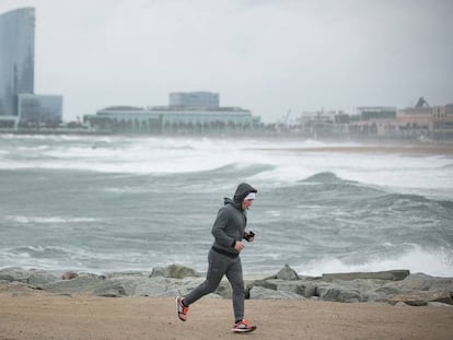 Un hombre corre por un espigón de la Barceloneta durante el temporal.