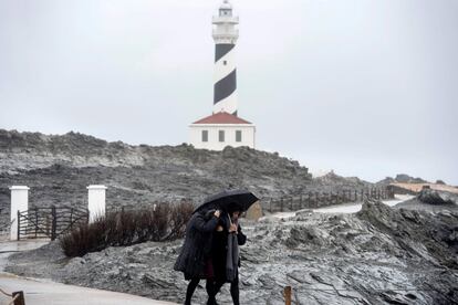 Dos personas caminan por las inmediaciones del faro de Faváritx, en el municipio menorquín de Mahón, este domingo.