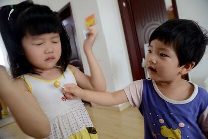 La pequeña Jiang trata de animar a su hermana mayor, que ha sido castigada a limpiar el suelo en el que ha tirado comida.