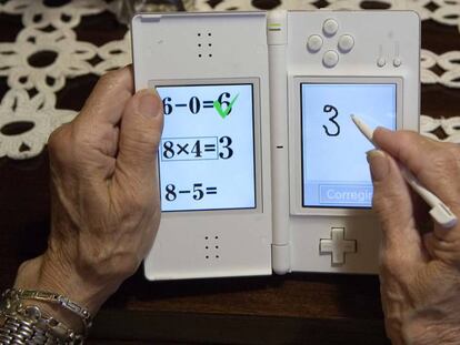 Una persona mayor juega a la aplicación Brain training en la consola Nintendo DS.