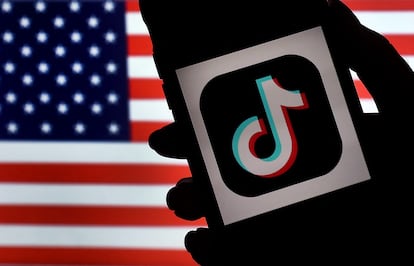 El logo de la red social TikTok en un móvil delante de la bandera de Estados Unidos en Arlington, Virginia.