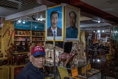 Un jubilado chino pasea frente a imágenes de Xi Jinping y Mao Zedong, en una tienda de recuerdos en Jinggangshan (China), 