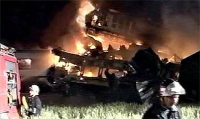 Los bomberos apagan el fuego en los vagones de los trenes incendiados tras la colisión.