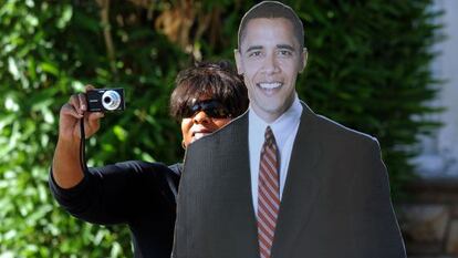 Una mujer se fotografía junto a un póster gigante de Obama.