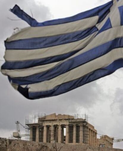 Una bandera griega ondea delante del Partenón de la Acrópolis de Atenas, en Grecia.