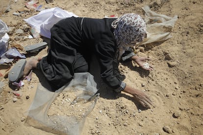 Una mujer palestina intenta recoger arroz, lentejas y frijoles de paquetes de ayuda humanitaria que fueron lanzados desde el aire y se rompieron al impactar sobre el suelo, el 5 de agosto en Ciudad de Gaza.
