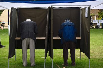 El Gobierno optó por mantener la cuarentena que rige en algunas ciudades del norte y sur del país, pero permitirá concurrir a votar sin restricciones y sin necesidad de permisos especiales. En la imagen, dos hombres eligen su voto en unas cabinas.