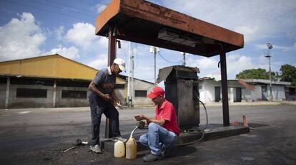 Dos hombres rellenan de gasolina unos bidones en Chivacoa (Venezuela), el 13 de octubre de 2019.