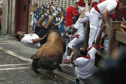 Un toro de Cebada Gago embiste a un mozo a su paso por la curva de Mercaderes, durante el segundo encierro de los Sanfermines de 2016.