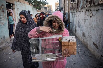 Una joven sujeta la jaula de un pájaro mientras huye tras un ataque israelí en Rafah, este jueves.  