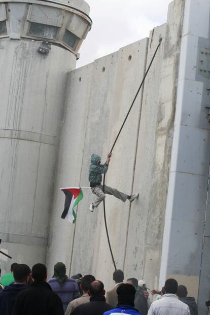 Un manifestante palestino trata de escalar el muro del puesto fronterizo entre Jerusalén y Belén.