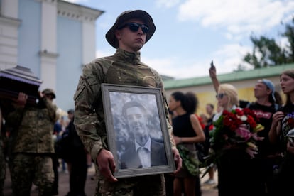 Un soldado sostiene una foto del activista y soldado Roman Ratushnyi durante un servicio conmemorativo en Kiev, el 18 de junio de 2022. 