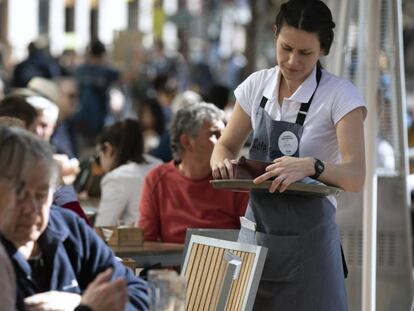 Una camarera atiende a unos clientes en una terraza en Valencia.