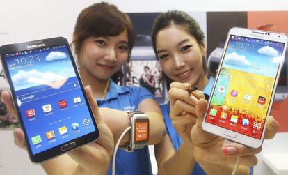 Dos azafatas muestran la nueva tableta Samsung Galaxy Gear smartwatch y el móvil Galaxy Note 3 (centro) en un evento promocional en la sede de Samsung en Seúl (Corea del Sur)